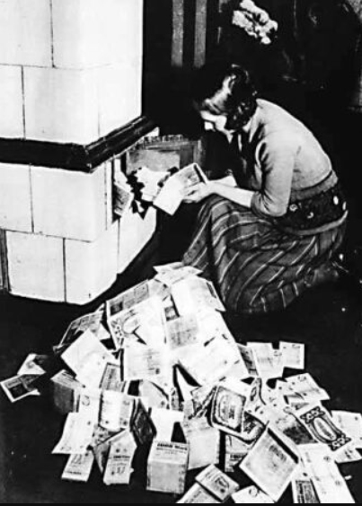 Mujer alimentando su caldera de calefacción con billetes. Alemania, 1923.